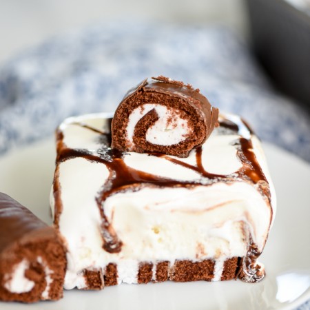 Swiss Rolls Ice Cream Cake - This easy ice cream cake recipe is perfect for summer! Layers of Swiss Rolls, vanilla ice cream, whipped cream and chocolate sauce.