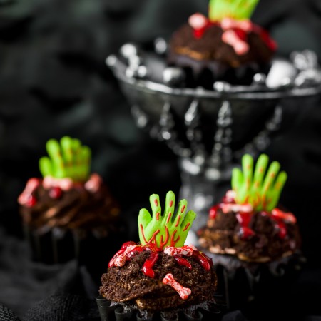 Chocolate cupcakes decorated with green zombie hands and red icing