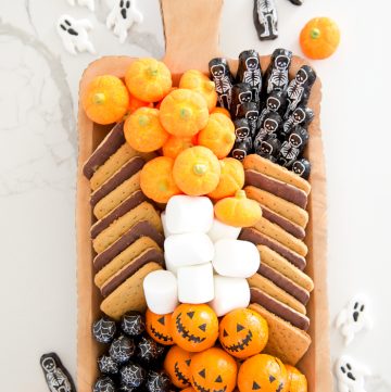 S'mores board ideas for Halloween with pumpkin marshmallows, pumpkin chocolate balls, and skeleton chocolate bars
