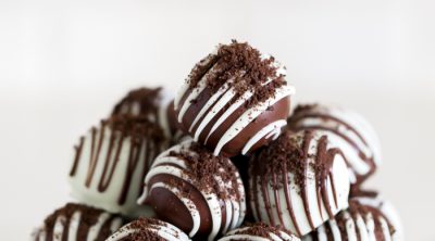 Gluten free Oreo ball recipe dipped in chocolate, with chocolate drizzle, and crushed oreo crumbs