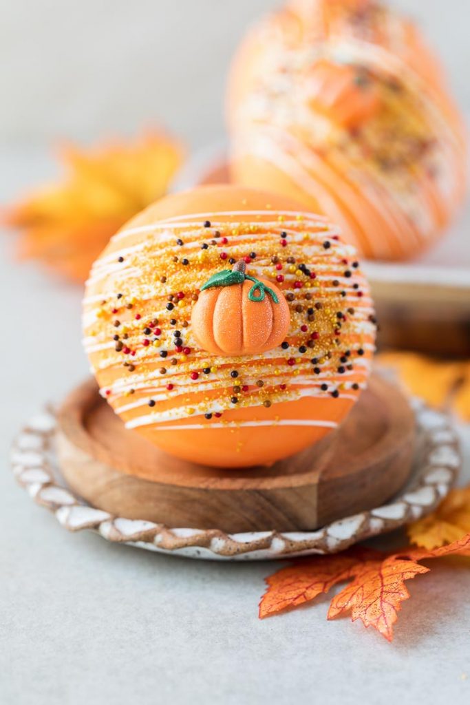 orange pumpkin spice hot chocolate bomb with pumpkin icing decorations