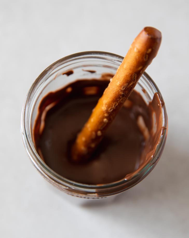 dipping pretzel rods in melted chocolate