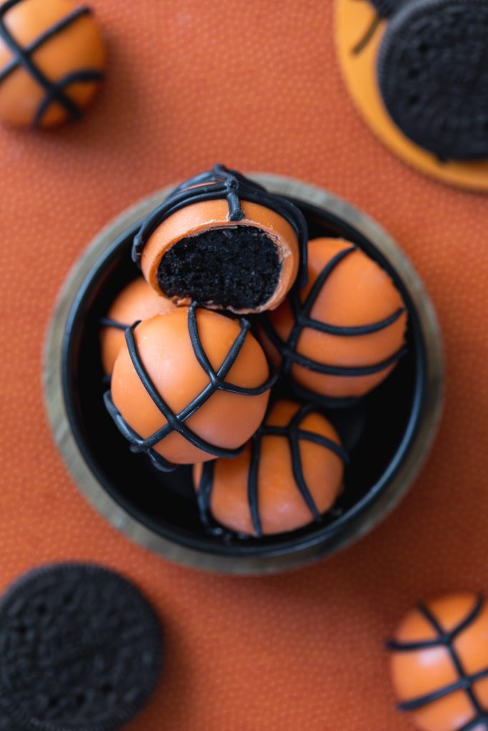 orange chocolate dipped oreo cookie balls decorated into basketballs
