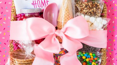 basket filled with ice cream sundae toppings and wrapped in a pink bow