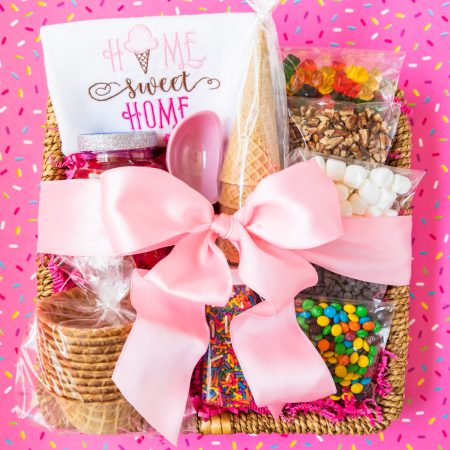 basket filled with ice cream sundae toppings and wrapped in a pink bow