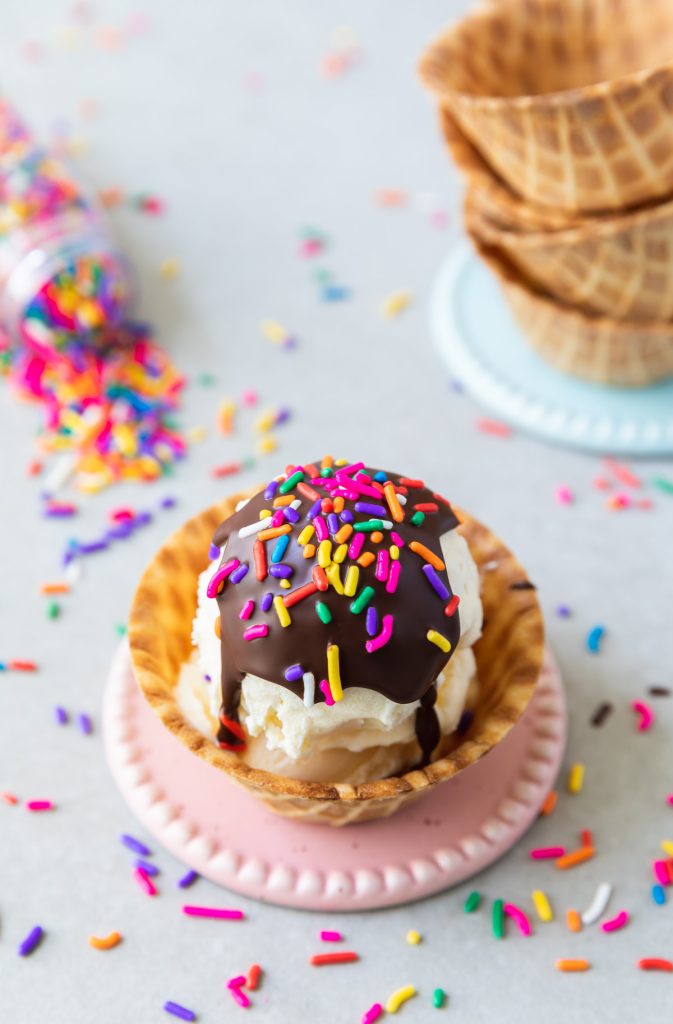chocolate shell topping on a scoop of ice cream in waffle bowl with sprinkles