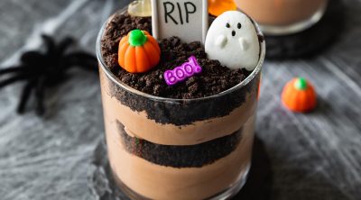 chocolate pudding layered with oreo cookies decorated into graveyard cups with tombstones