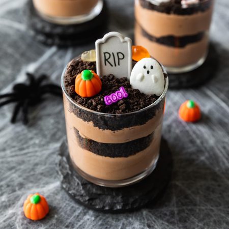 chocolate pudding layered with oreo cookies decorated into graveyard cups with tombstones