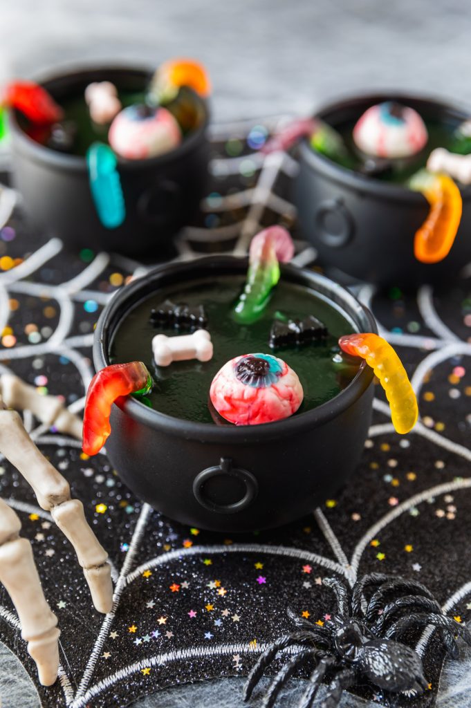 green jello in Halloween cauldron cups with gummy worms