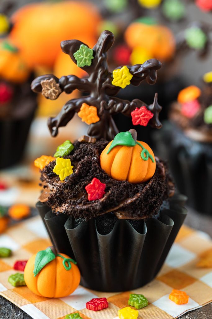 chocolate cupcakes with fall leaf sprinkles and pumpkin candy decorations