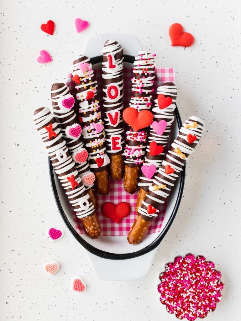 chocolate-covered pretzel rods with red and pink heart sprinkles