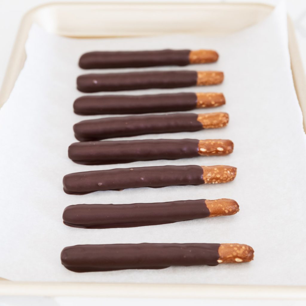 pretzel rods dipped in chocolate on parchment paper