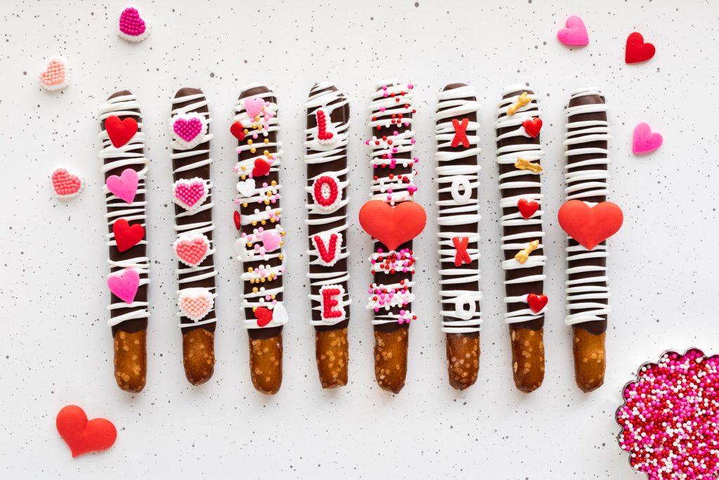 milk chocolate pretzels with white chocolate drizzle decorated with Valentine's Day sprinkles