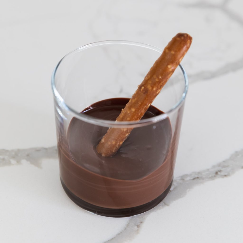 melted milk chocolate in a cup with pretzel rod
